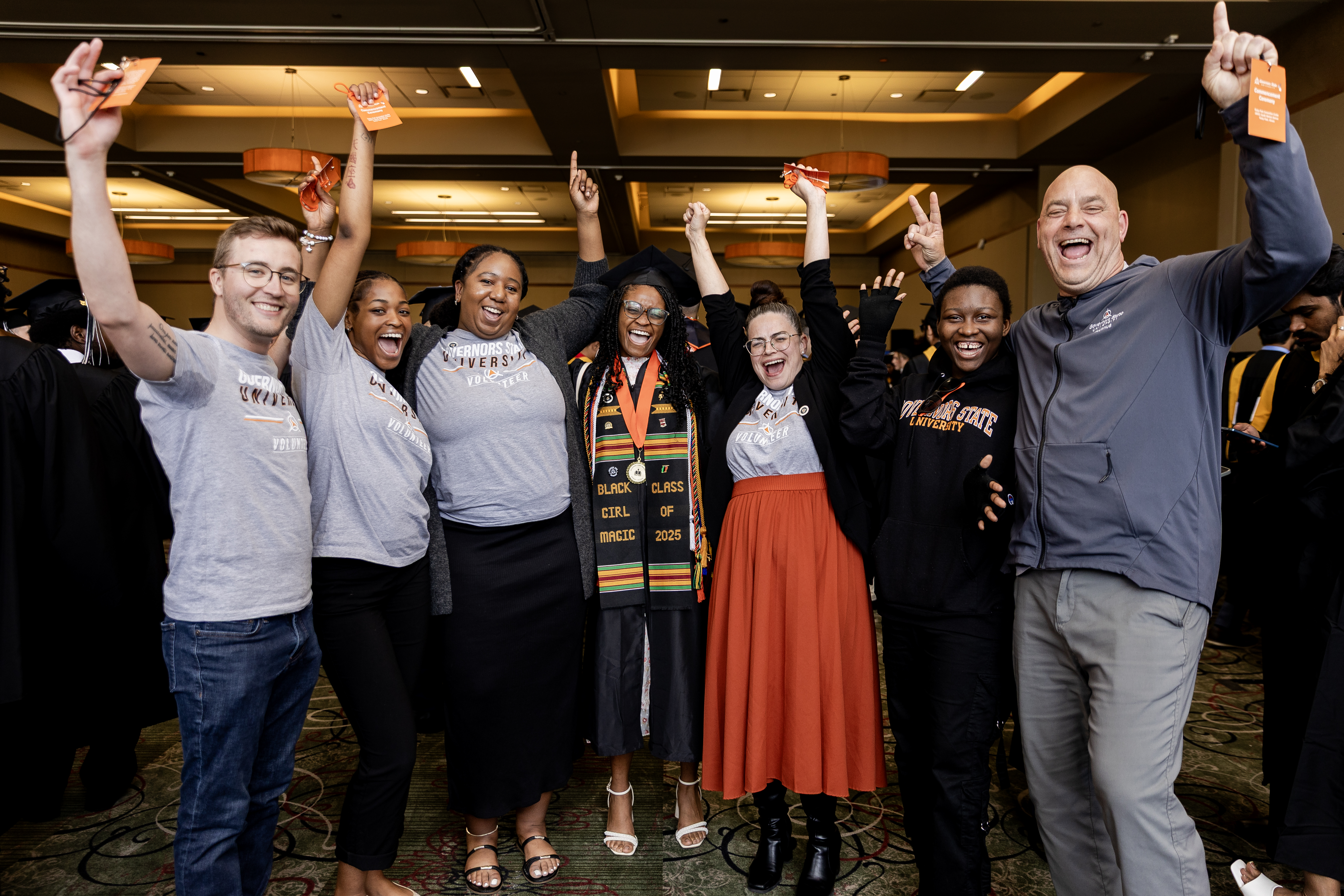 A photo depicting six Alumni Relations team members celebrating with a Governors State University graduate. 